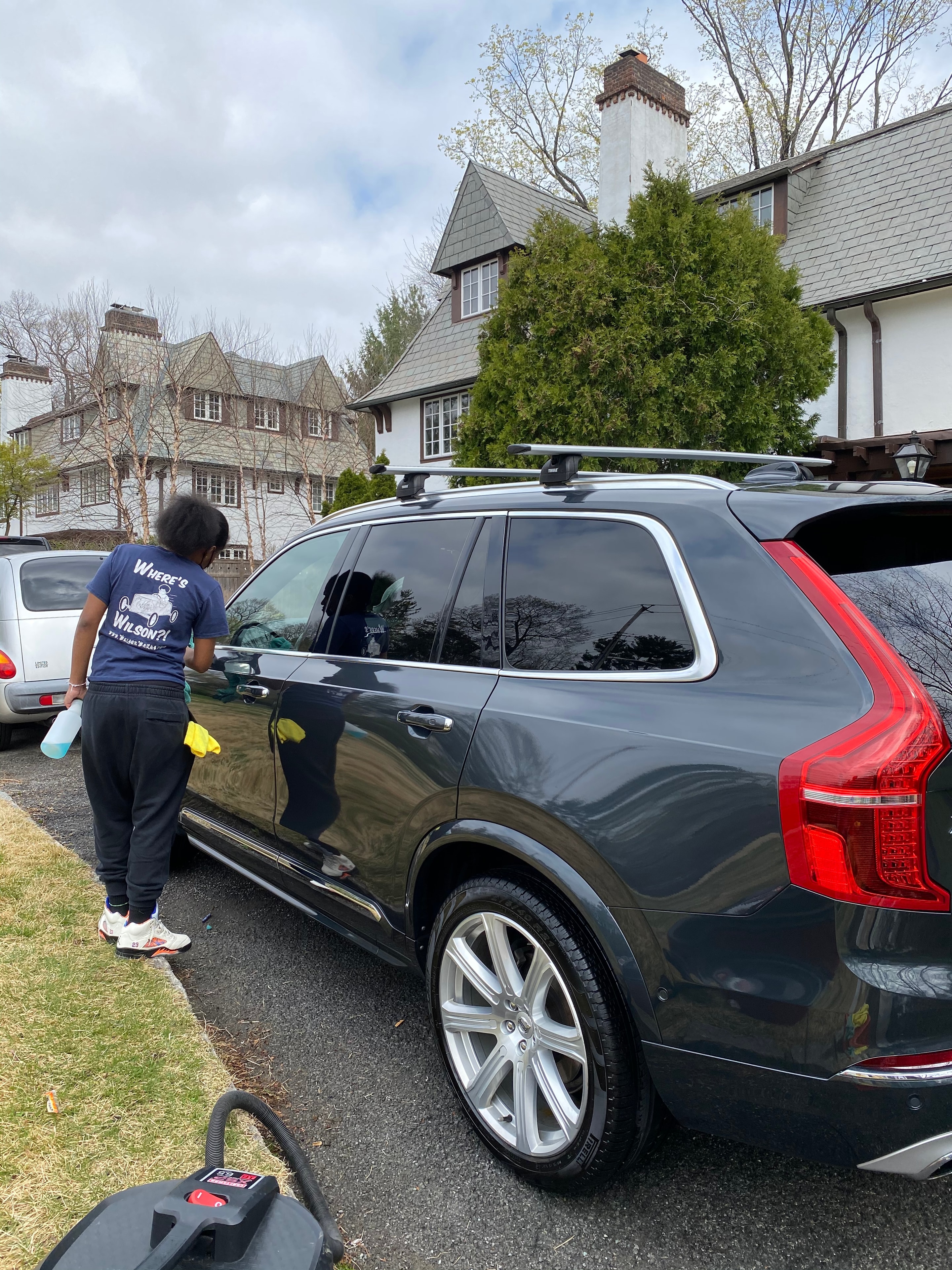 Wilson Waxes technician detailing a black SUV in a residential driveway