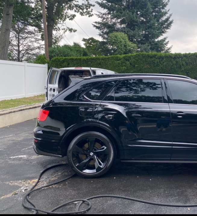 Black Bentley Bentayga being detailed in a parking lot