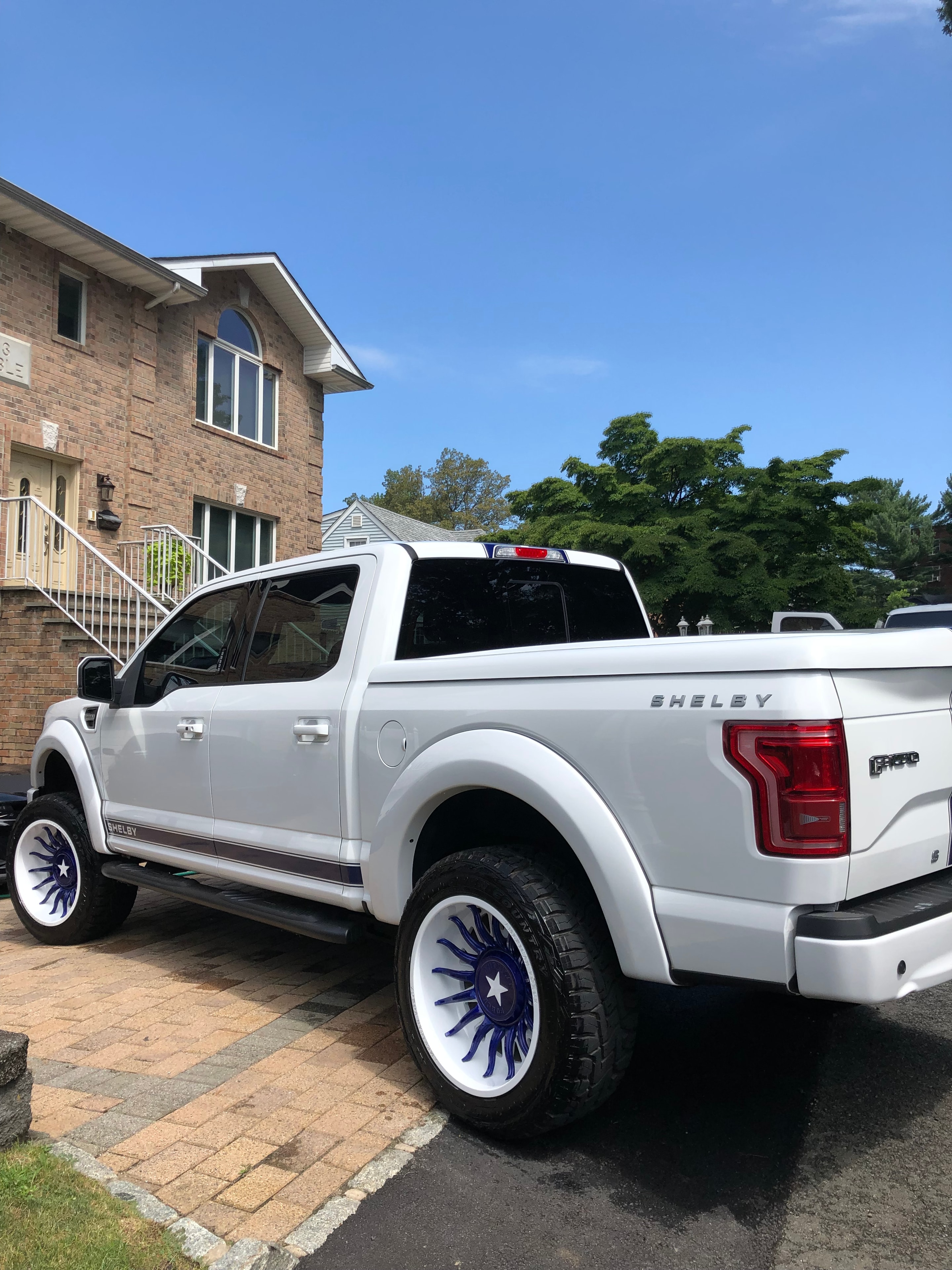 White Shelby F-150 truck with custom wheels detailed on a cobblestone driveway